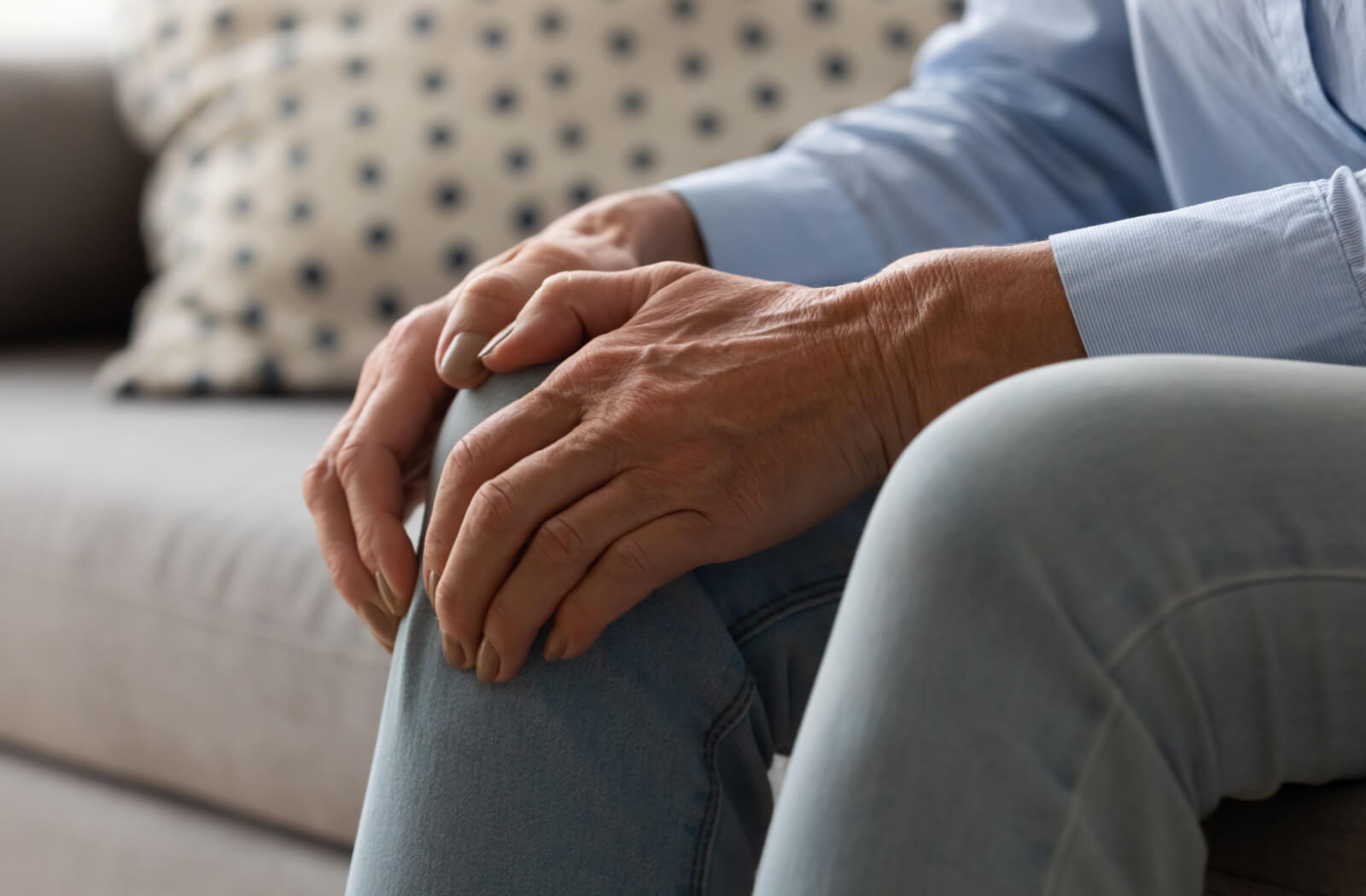 A close-up image of an older adult rubbing their right knee in discomfort due to exercising too much.