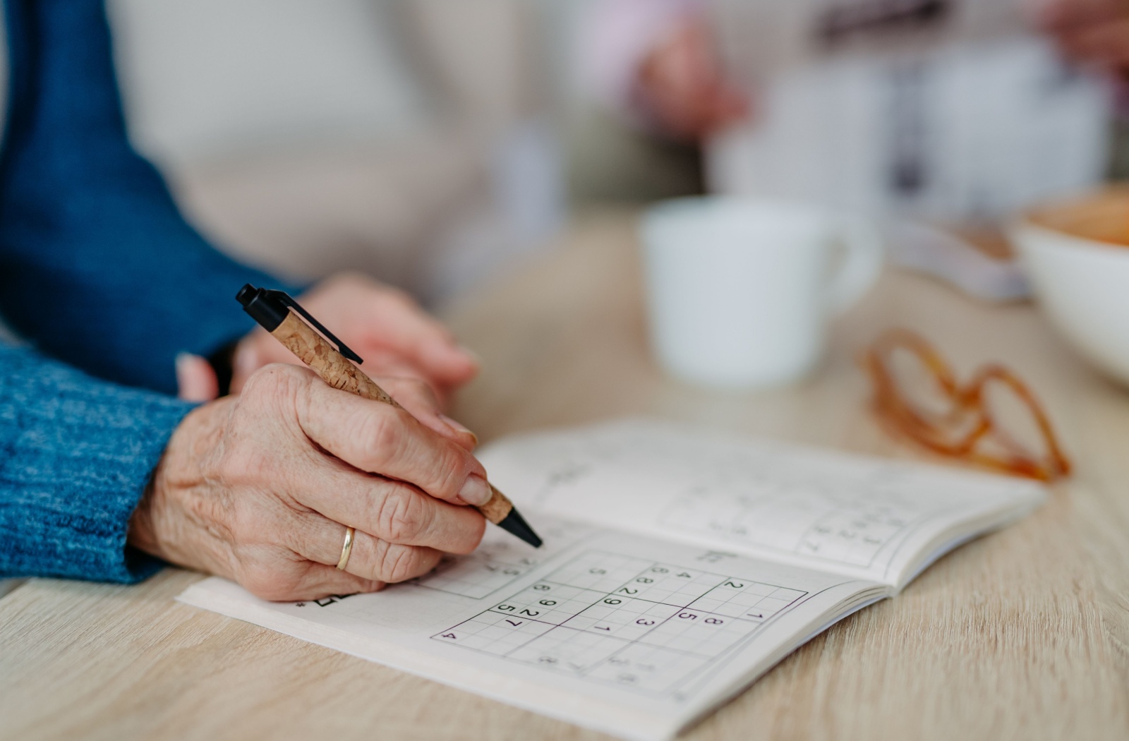 Close up of a senior woman doing a sudoku puzzle.