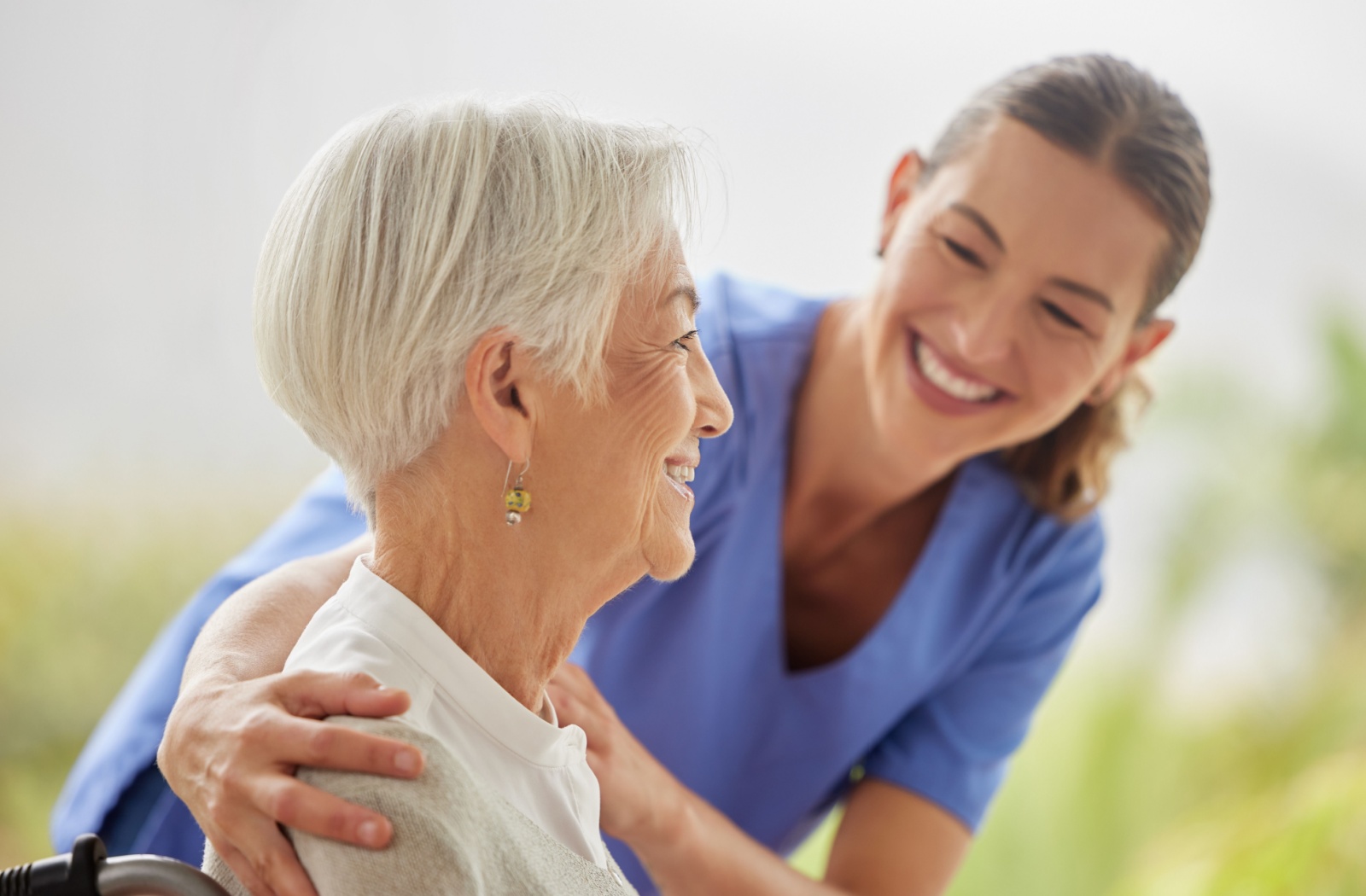 A caregiver and older resident in respite care on a walk out on the lawn of a senior living community.