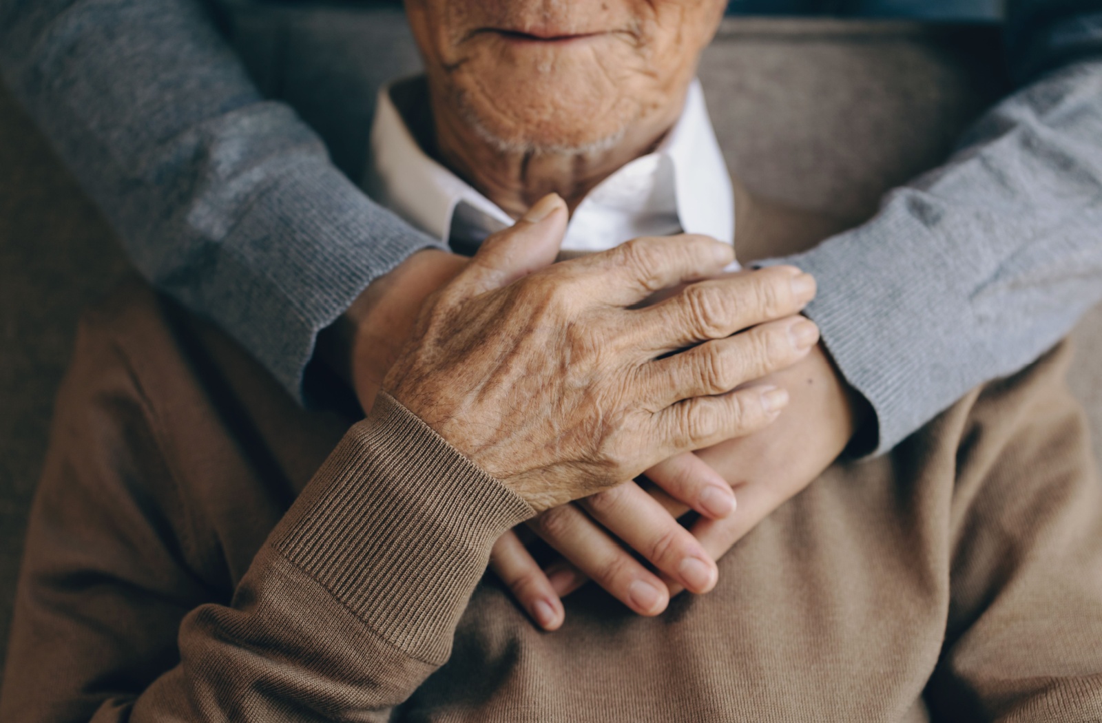 A close-up image of a caregiver hugging an older resident from behind in respite care.