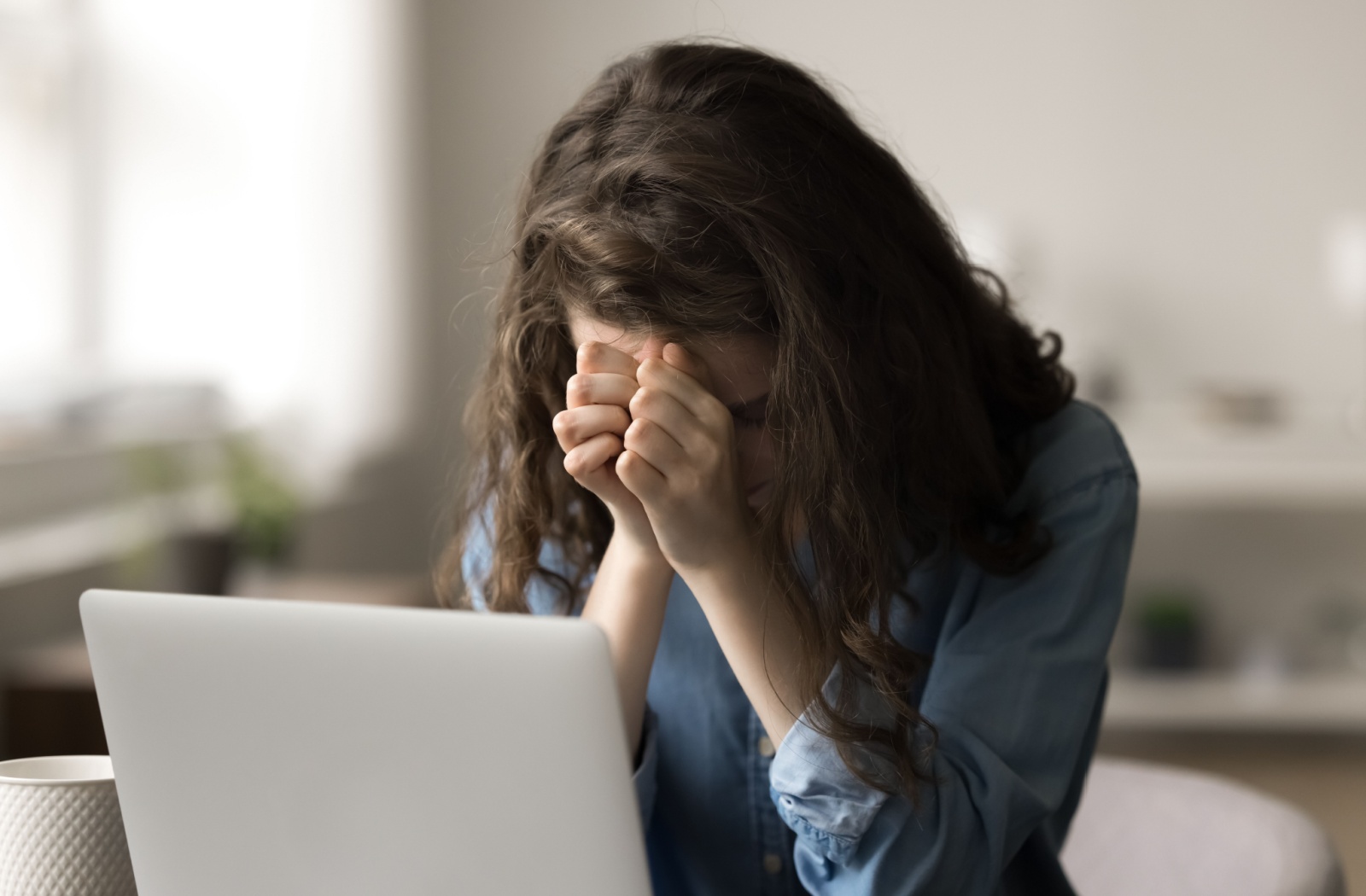An adult child rubbing their forehead due to stress from being a caregiver for their adult parent.