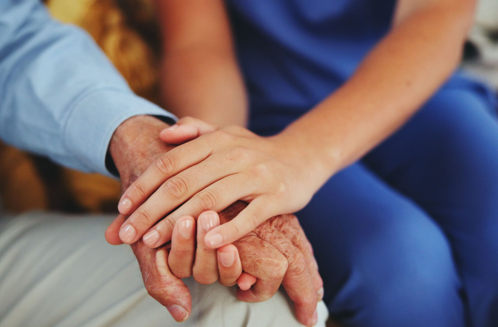 A caregiver in respite care touching the hand of an older resident to show them support.