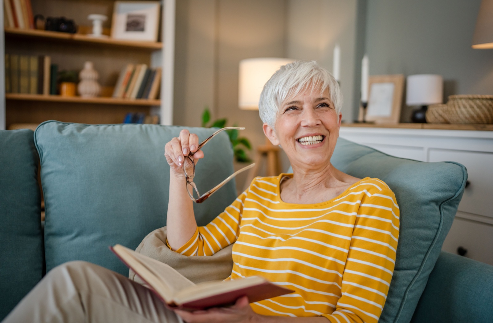 A senior enjoys reading a book in their senior living community apartment